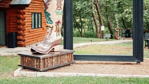 Eine Holzhütte mit Metalldach, einem Schild mit der Aufschrift 'Cabins on the Square' und einer großen Holzskulptur eines Reiters mit Pferd.