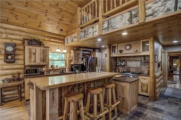 L’intérieur d’un chalet en bois rustique, doté d’un grand îlot de cuisine, de tabourets de bar et d’un coin repas.