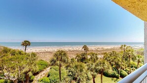 A balcony with a view of a beach, palm trees, and a clear sky. - Updated Two Bedroom Fourth Floor Captains Walk Condo, Oceanfront Views (Hilton Head)