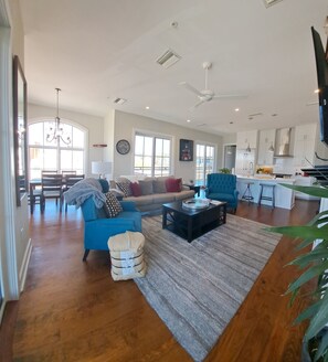 A spacious living room with a large sofa, a coffee table, and a dining area with a chandelier. - Penthouse apartment located less than a block away from square (Oxford)