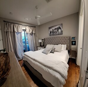 A modern bedroom with a large bed, a ceiling fan, and a window with curtains. - Penthouse apartment located less than a block away from square (Oxford)