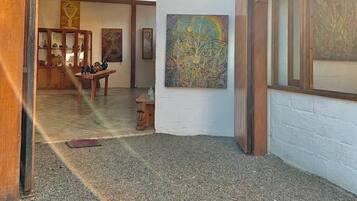 Una galería al aire libre con una pérgola de madera, un cuadro abstracto de gran tamaño y una exhibición de esculturas.