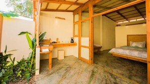 A room with a bed, a small desk, a chair, and a window. - Galería Suites San Pancho (San Francisco)