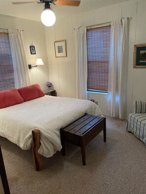 A bedroom with a bed, a wooden bench, a nightstand, a lamp, and two windows with curtains. - Concan Frio River Cabin  (Concan)
