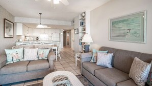 A spacious living room with a grey sofa set, a dining area with a white table, and a kitchen in the background. - 3 Bedroom/2 Bath Oceanfront Timeshare in Myrtle Beach (Murrells Inlet)