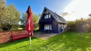 A blue house with a sloped roof and a brick wall. - Blue House - arrive and feel at home (Hülseburg)