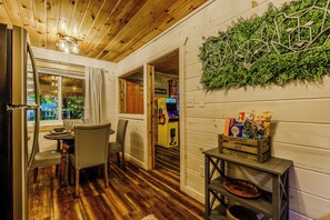 Interior de madera con comedor, planta colgante y una pequeña mesa con una caja de aperitivos.