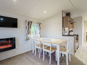 A modern kitchen with a dining area, a flat-screen TV, and a fireplace.