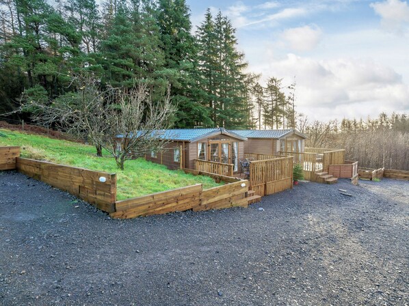 A cabin with a deck, surrounded by a forest.