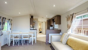 A compact living space with a dining area, kitchenette, and a sofa with a window view.