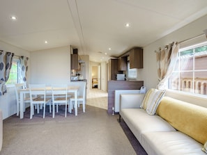 Un espacio habitable compacto con comedor, kitchenette y sofá con vista al exterior.