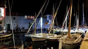 Boats docked at a picturesque harbor pier, surrounded by calm waters reflecting the surrounding lights.