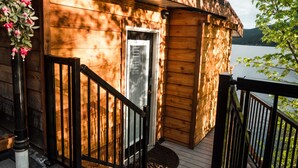 A wooden cabin with a deck, a door, and a view of a lake. - Lakefront Hideaway w/ beautiful views, quiet area, private lake access & dock! (Christina Lake)