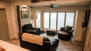 A living room with a fireplace, a sofa, a chair, and a television. - Lakefront Hideaway w/ beautiful views, quiet area, private lake access & dock! (Christina Lake)