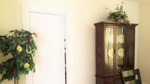 A room with a wooden cabinet, a chair, and a potted plant. - Brick House Retreat at the Heart of Hamlet (HAMLET)
