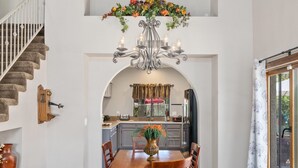 A dining area with a wooden table and chairs, a chandelier, and a colorful painting above. - 😎🏜️ <br>NEW Beautiful Relaxed Elegant Retreat.2330 sf 4b3b.  (Glendale)