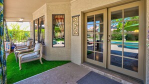 A covered patio area with a pool view, a seating area with a bench and chairs, and a decorative wall panel. - 😎🏜️ <br>NEW Beautiful Relaxed Elegant Retreat.2330 sf 4b3b.  (Glendale)