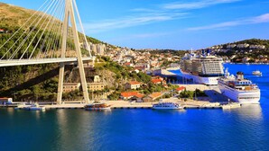 Un puente moderno de cables que cruza un cuerpo de agua, con un crucero amarrado cerca.
