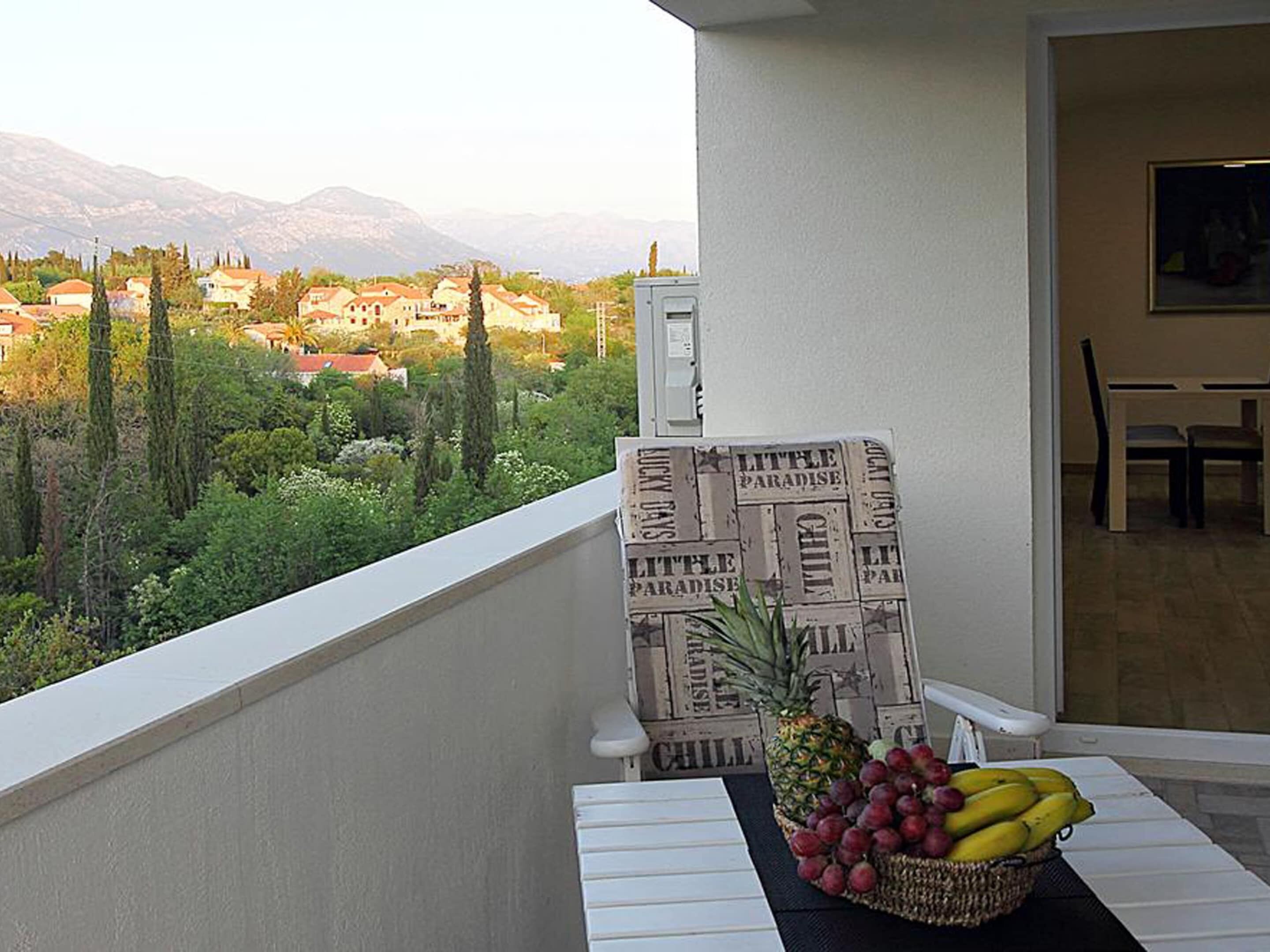 Ein Balkon mit Tisch, Stuhl und Obstkorb.