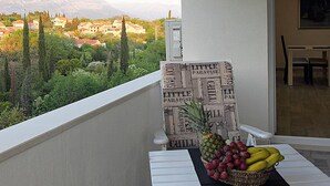 Un balcón con una mesa, una silla y una cesta de frutas.