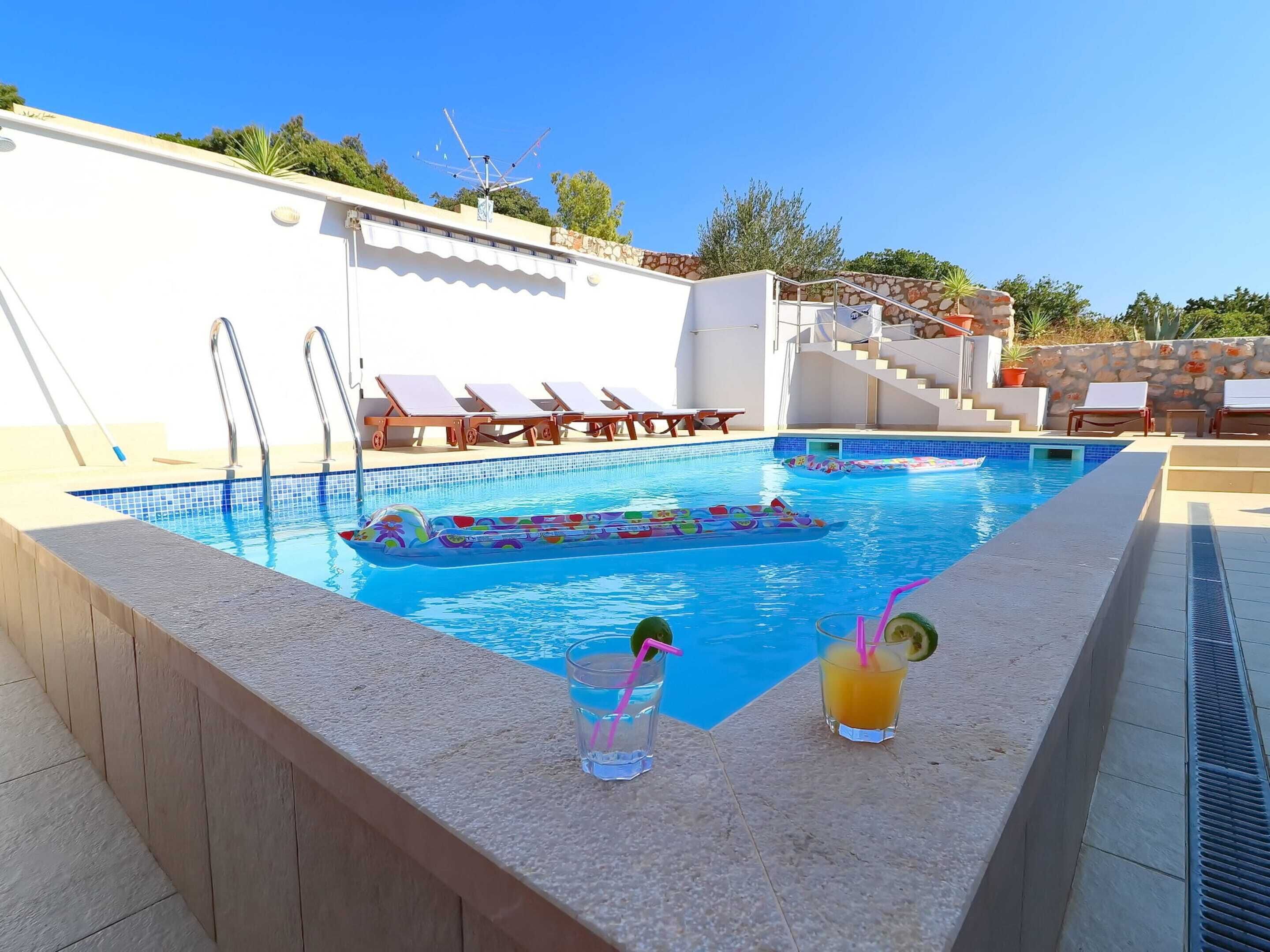 A swimming pool with lounge chairs and a stone wall.