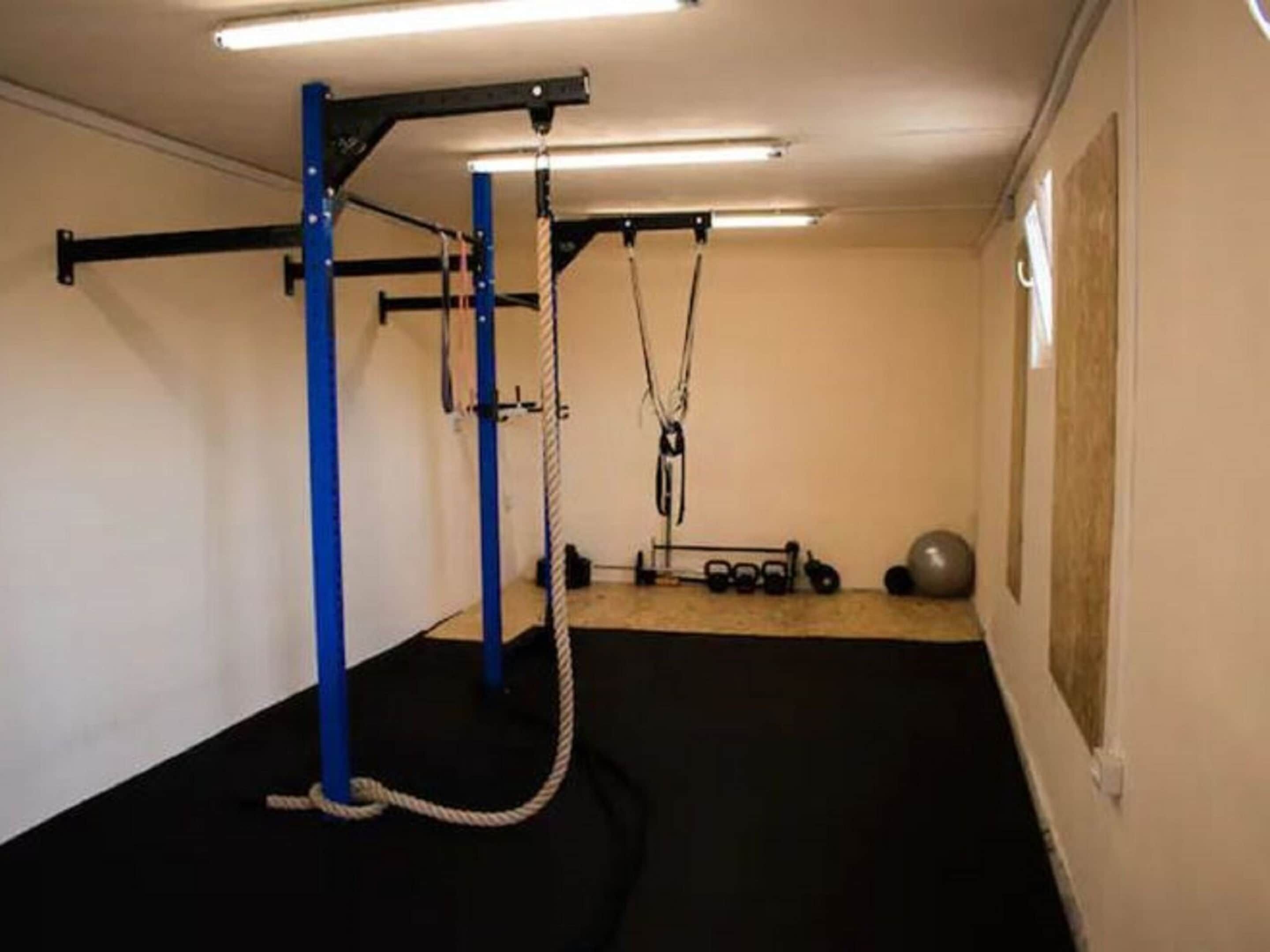 Un gimnasio con barra de dominadas, banco de pesas y pelotas de ejercicio.