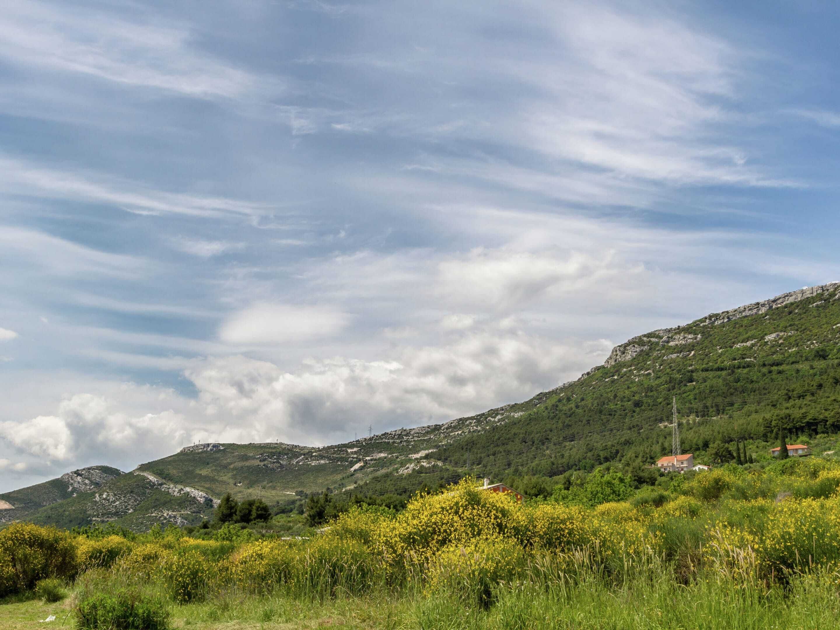 A mountainous landscape with a clear sky and scattered clouds.