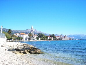 A coastal town with historic buildings, a prominent church tower, and clear blue waters. - Modern Apartment in Kastel Stari (Kastela)