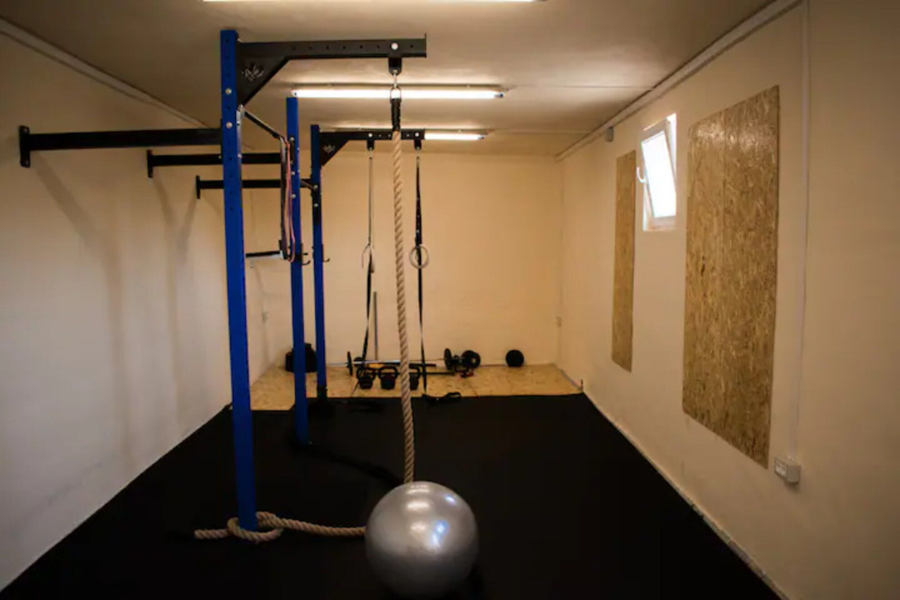 Ein Fitnessraum mit Klimmzugstange, Seilen und Gewichtsplatten.