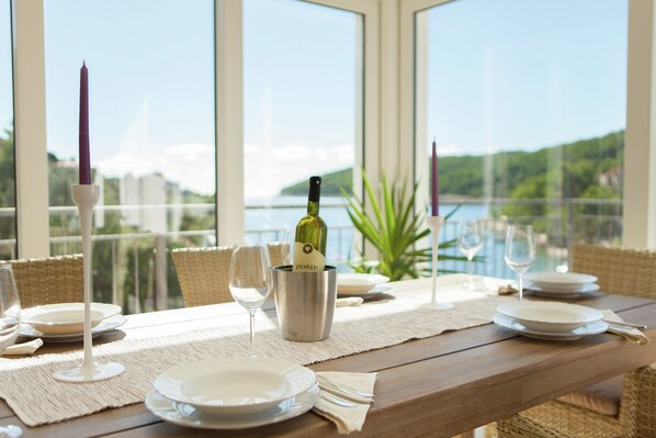 A dining table set with plates, glasses, and a bottle of wine, overlooking a scenic view.
