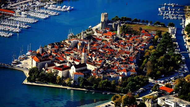 An aerial view of a coastal town with historic buildings, a marina, and a prominent castle. - Apartment in Arbanija With Terrace (Trogir)
