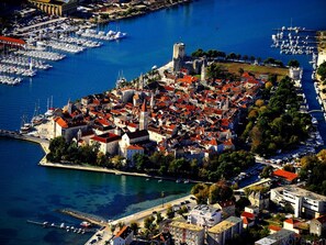 An aerial view of a coastal town with historic buildings, a marina, and a prominent castle. - Apartment in Arbanija With Terrace (Trogir)
