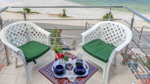A terrace with two white chairs with green cushions, a table with a tray of blue cups and a glass, and a view of the sea. - Apartment in Arbanija With Terrace (Trogir)