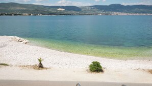 A coastal view with clear water, a sandy beach, and distant mountains. - Apartment in Arbanija With Terrace (Trogir)