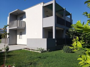 A modern two-story building with a flat roof, large windows, and a balcony on the ground floor. - Apartment in Kastel Stafilic Near the Beach (Kastela)