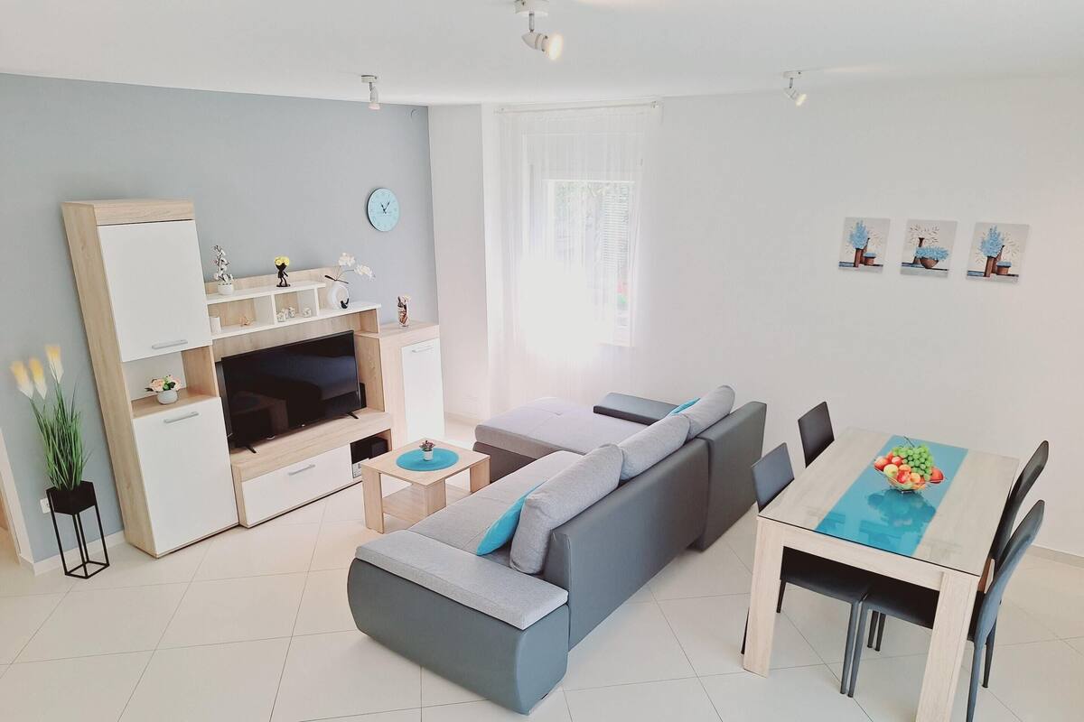 Un salon moderne avec un canapé, un téléviseur et un coin repas.