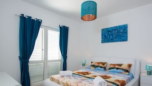 A modern bedroom with a bed, curtains, a painting, and a lamp. - Apartment in Seget Donji Near Trogir Old Town (Seget)