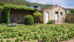 A stone building with a tiled roof, surrounded by a garden with various plants and flowers. - Sea-view Retreat, Kastel (Kastela)