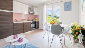 A modern kitchen with a built-in oven and a dining area with a table and chairs. - Sea-view Retreat, Kastel (Kastela)