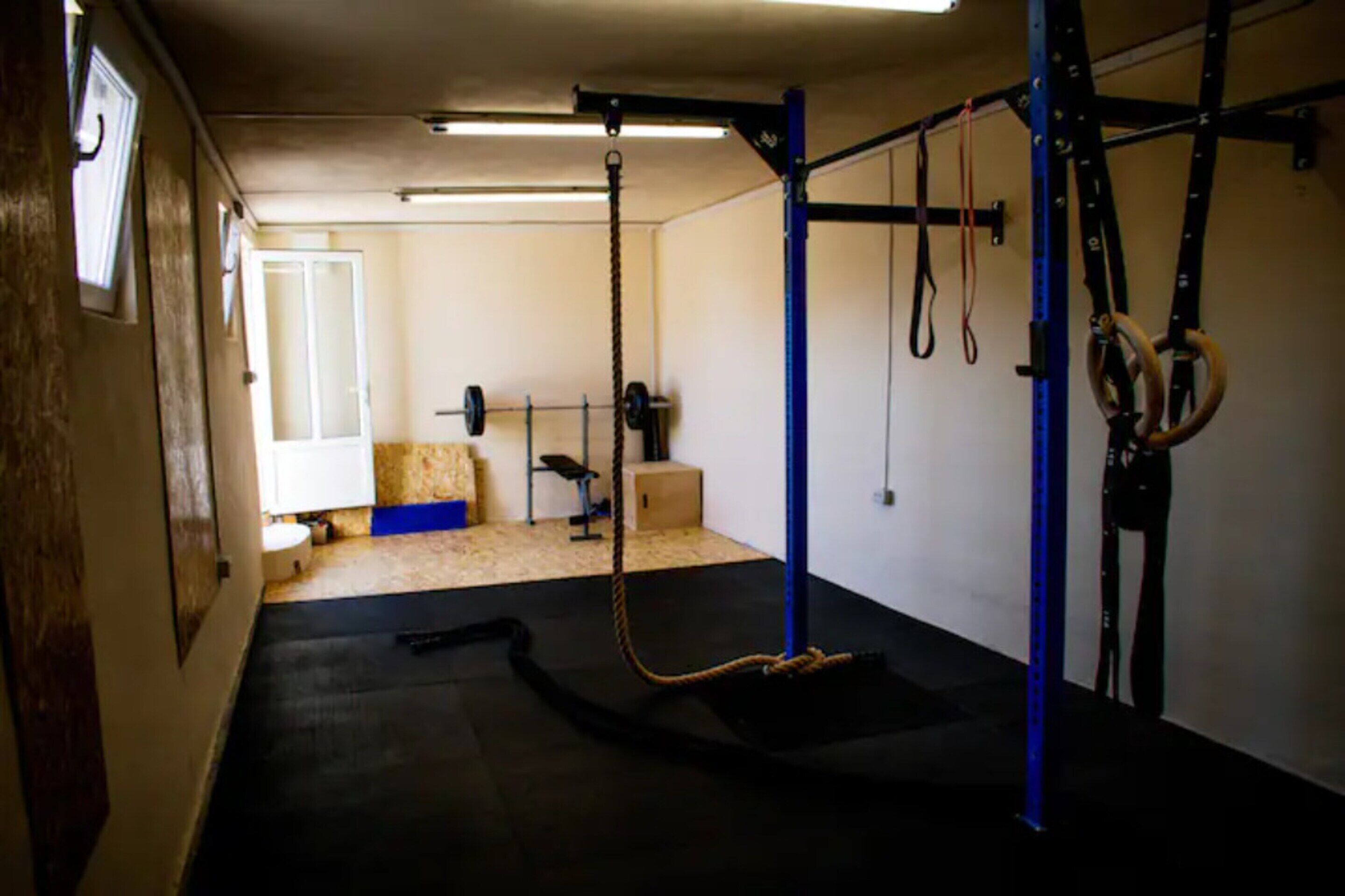 A gym with a pull-up bar, a squat rack, and a weight bench.