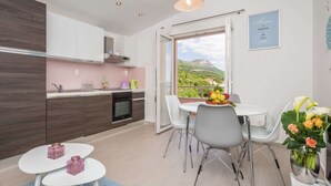 A modern kitchen with white cabinets, a built-in oven, and a dining area with a table and chairs. - Sea-view Retreat, Kastel (Kastela)