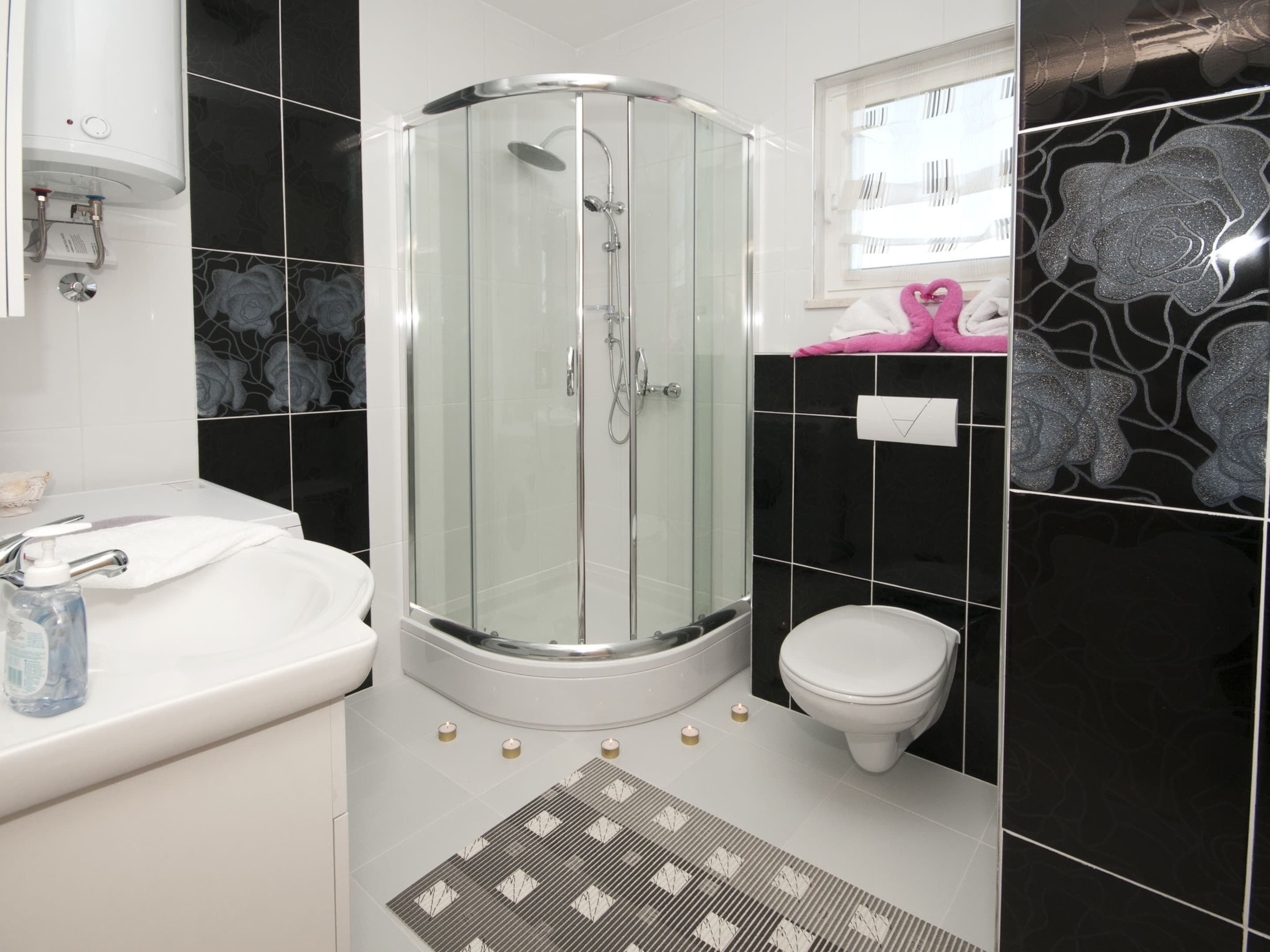 A modern bathroom with a glass-enclosed shower, a white sink, and a toilet.
