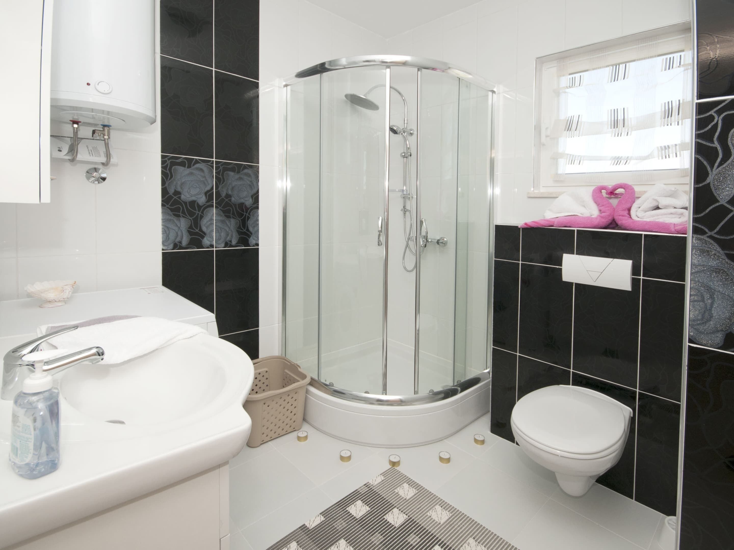 Een moderne badkamer met een douchecabine van glas, een wit wastafelmeubel en een toilet.