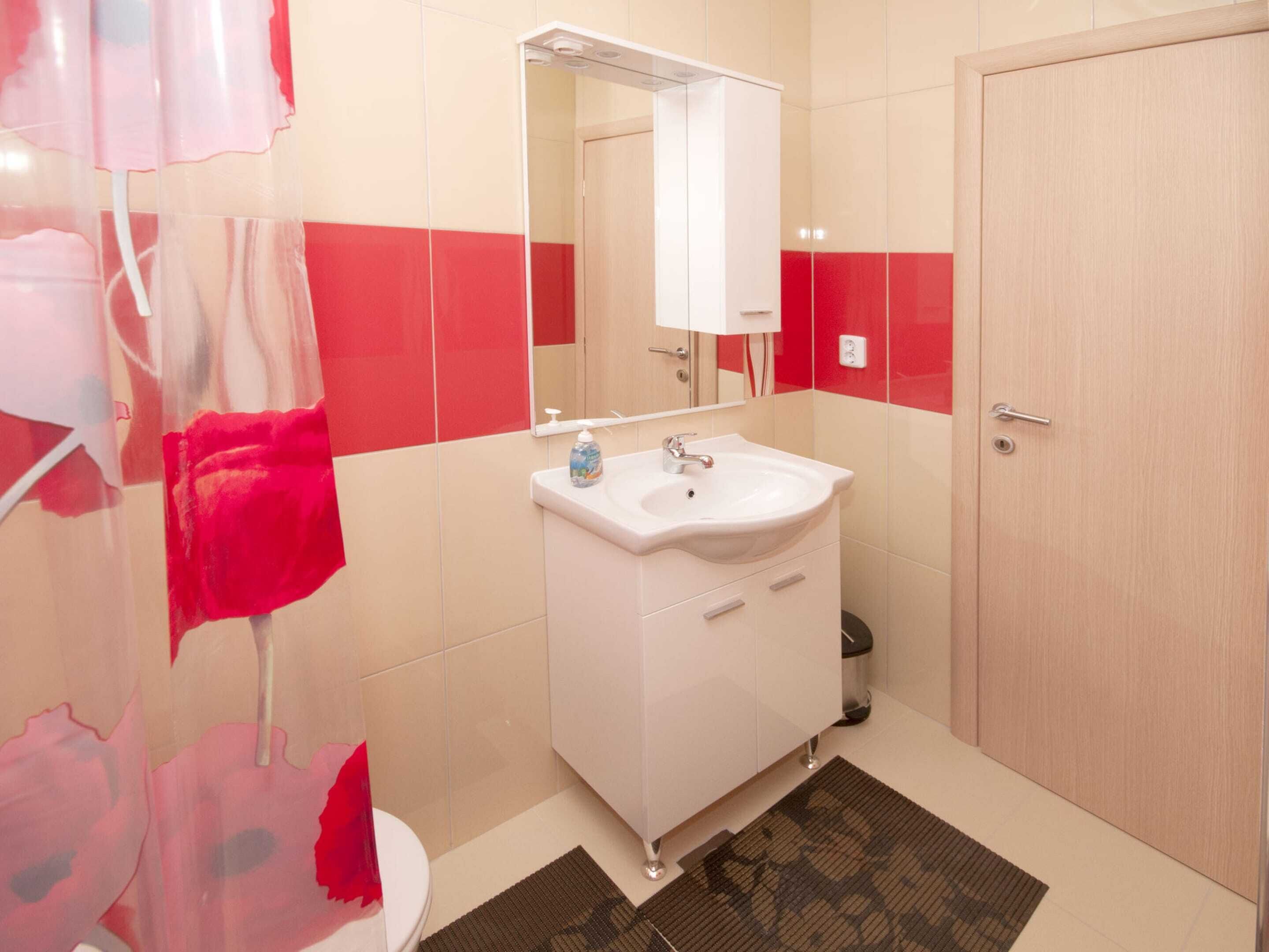 Un baño con lavamanos blanco, espejo y una puerta.