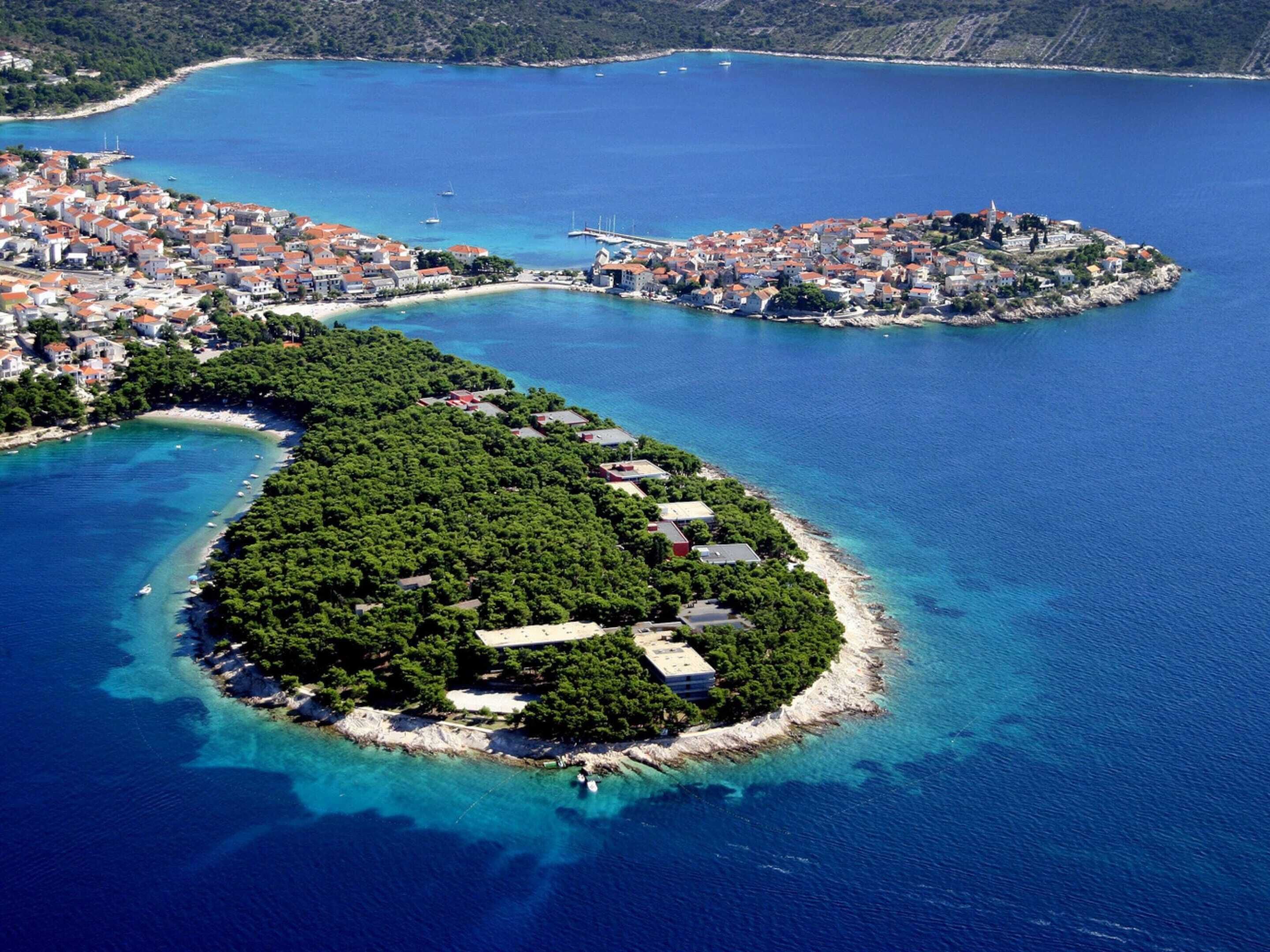 Vista aérea de un pueblo costero con una isla central cubierta de vegetación densa y algunos edificios.