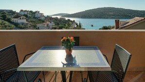 A balcony with a table and chairs, a potted plant, and a view of a lake and hills. - Holiday Home With Outdoor Hot Tub, Near the Sea (Marina)