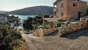 A two-story building with a stone facade, a red-tiled roof, and a balcony. - Holiday Home With Outdoor Hot Tub, Near the Sea (Marina)