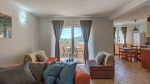 A living room with a sofa, a small table, and a balcony with a view. - Holiday Home With Outdoor Hot Tub, Near the Sea (Marina)