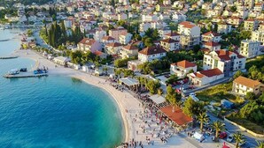 A coastal town with a sandy beach, a pier, and a boat docked at the pier. - Apartment in Okrug Gornji Near the Beach (Okrug)