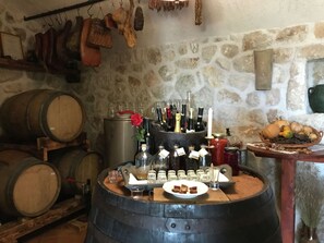 A rustic cellar with wooden barrels, a wine rack, and a variety of bottles and glasses.